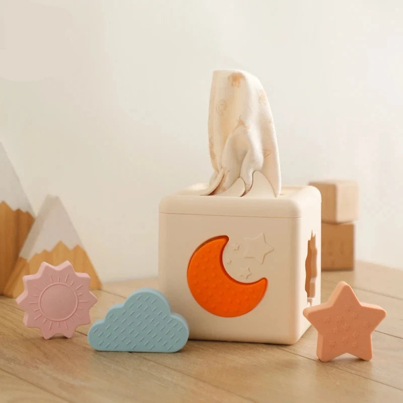 Babylove Silicone Tissue Box for kids aged 0-14+ years, free from high-concern chemicals. This Montessori toy enhances color recognition and shape pairing, made from high-quality silicone with a shape and nature theme. Ideal for developing early learning skills