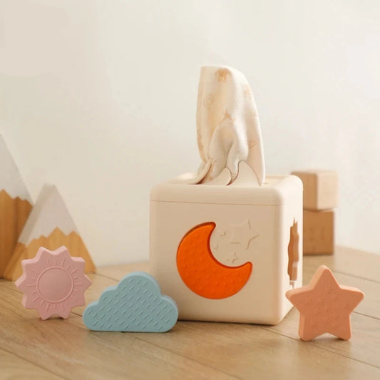 Babylove Silicone Tissue Box for kids aged 0-14+ years, free from high-concern chemicals. This Montessori toy enhances color recognition and shape pairing, made from high-quality silicone with a shape and nature theme. Ideal for developing early learning skills