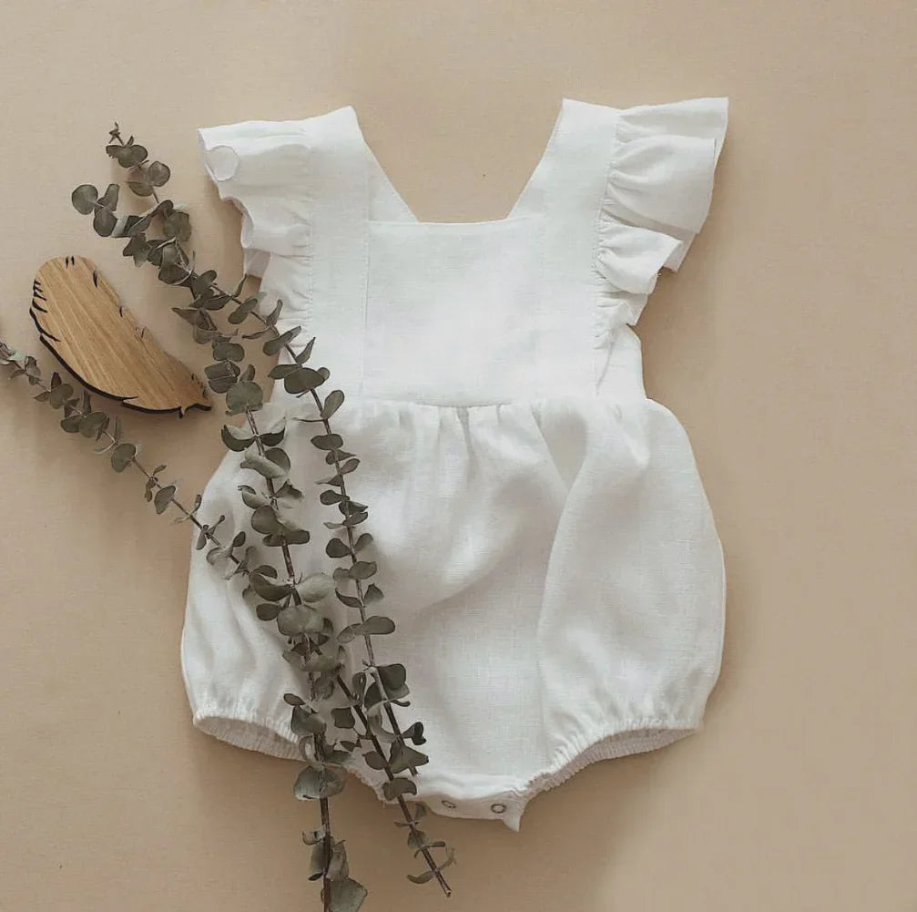 Shop BabyLove Ruffled Romper at BubeBaby, perfect for baby girls aged 0-24 months. Made from soft cotton, this sleeveless romper features a ruffled design and a covered button closure. Available in sizes for 3-24 months, it fits true to size and is ideal for summer