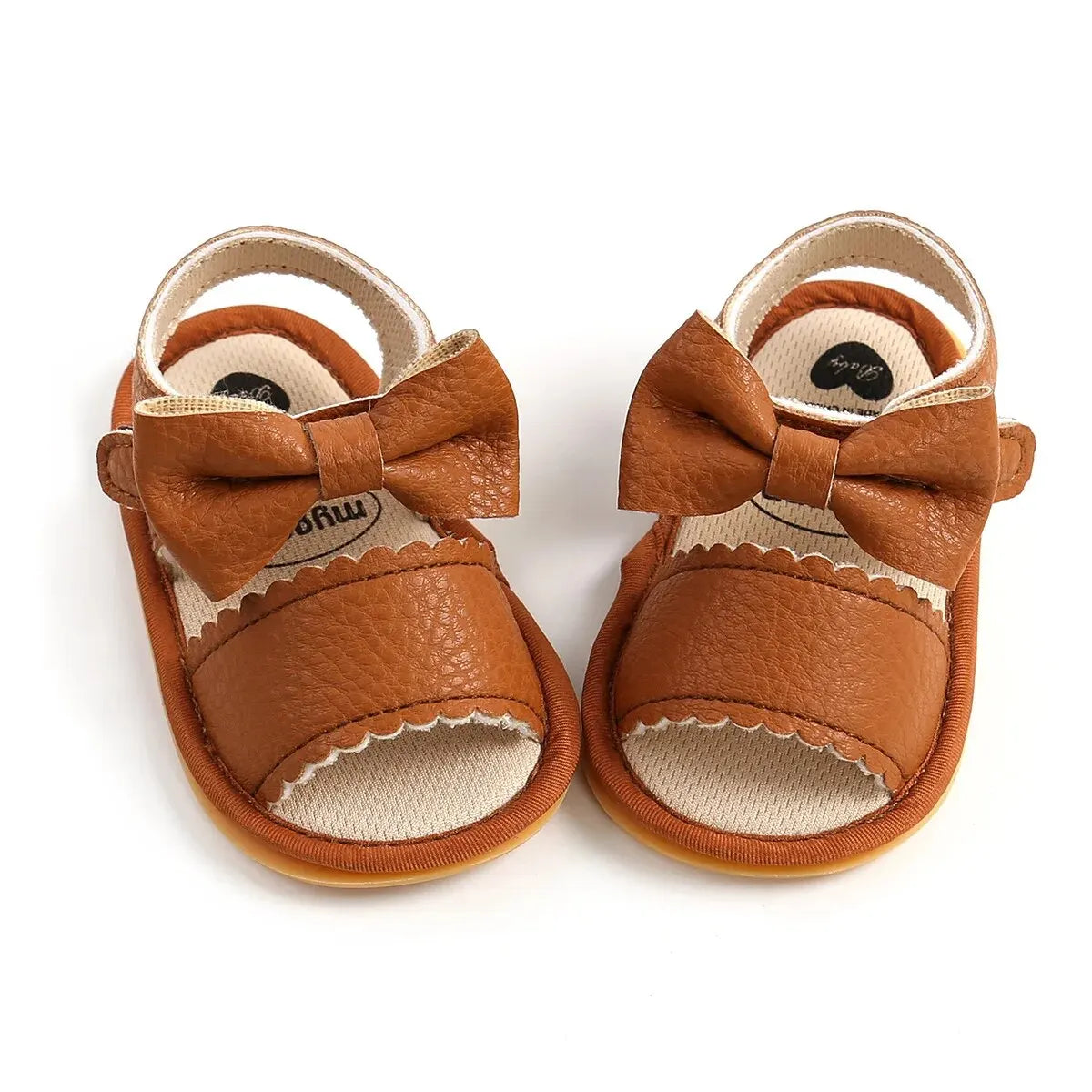 A cute pair of Bubebaby BabyLove  faux leather sandals for infants featuring an adorable bow detail. The sandals are designed for comfort and style, perfect for little ones to wear during warm weather. The adjustable strap ensures a secure fit while the soft sole provides cushioning for tiny feet