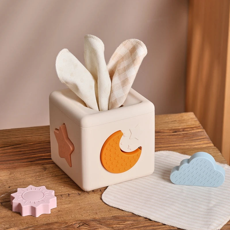 Babylove Silicone Tissue Box for kids aged 0-14+ years, free from high-concern chemicals. This Montessori toy enhances color recognition and shape pairing, made from high-quality silicone with a shape and nature theme. Ideal for developing early learning skills