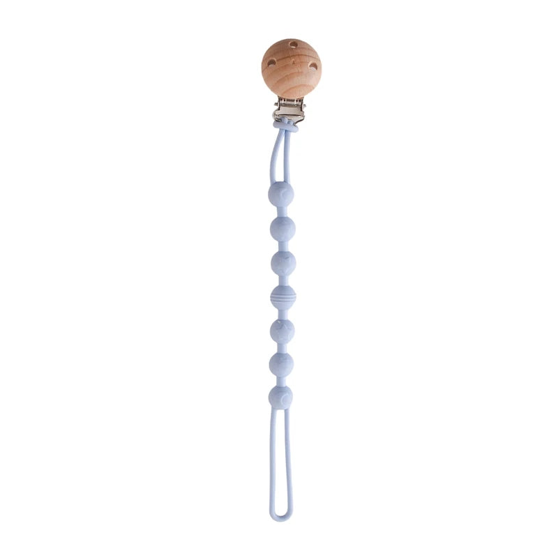 BabyLove Montessori Beech Wood and Silicone Beaded Pacifier Clip, a 20cm durable, BPA-free, phthalate-free, and latex-free accessory for babies aged 0-36 months. Features a solid color, wooden clip, and silicone strap. Versatile as a pacifier holder, soother chain, or teether toy. Safe and stylish design