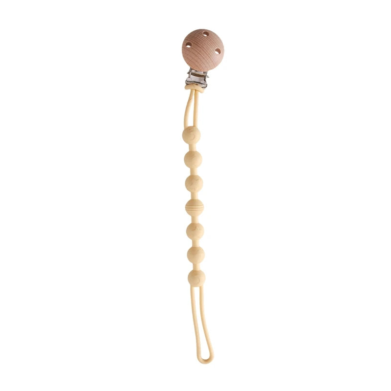 BabyLove Montessori Beech Wood and Silicone Beaded Pacifier Clip, a 20cm durable, BPA-free, phthalate-free, and latex-free accessory for babies aged 0-36 months. Features a solid color, wooden clip, and silicone strap. Versatile as a pacifier holder, soother chain, or teether toy. Safe and stylish design