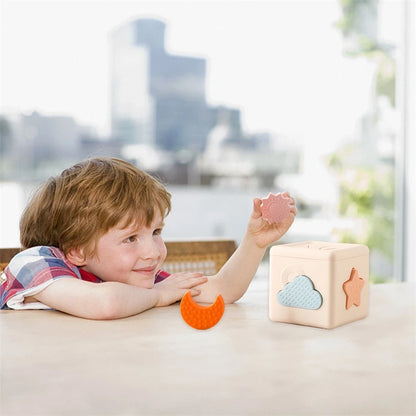 Babylove Silicone Tissue Box for kids aged 0-14+ years, free from high-concern chemicals. This Montessori toy enhances color recognition and shape pairing, made from high-quality silicone with a shape and nature theme. Ideal for developing early learning skills