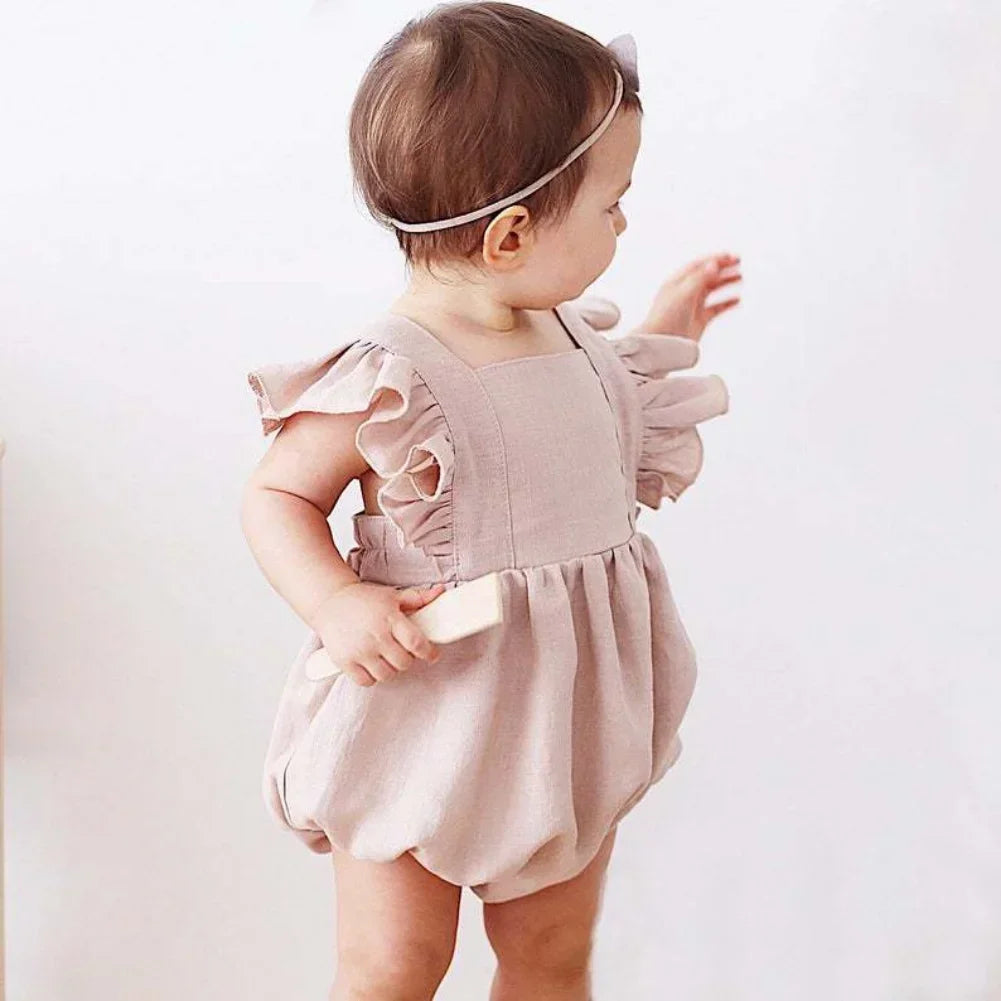 Shop BabyLove Ruffled Romper at BubeBaby, perfect for baby girls aged 0-24 months. Made from soft cotton, this sleeveless romper features a ruffled design and a covered button closure. Available in sizes for 3-24 months, it fits true to size and is ideal for summer