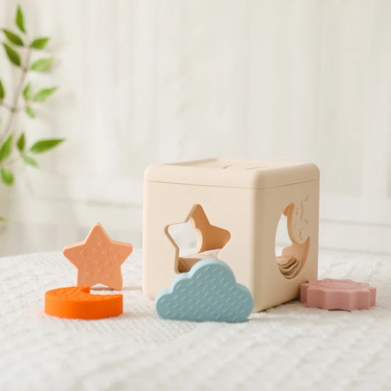 Babylove Silicone Tissue Box for kids aged 0-14+ years, free from high-concern chemicals. This Montessori toy enhances color recognition and shape pairing, made from high-quality silicone with a shape and nature theme. Ideal for developing early learning skills