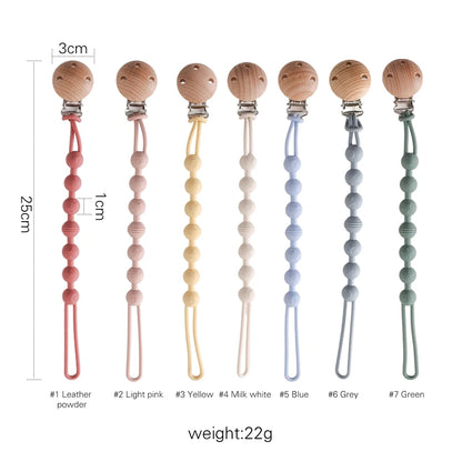 BabyLove Montessori Beech Wood and Silicone Beaded Pacifier Clip, a 20cm durable, BPA-free, phthalate-free, and latex-free accessory for babies aged 0-36 months. Features a solid color, wooden clip, and silicone strap. Versatile as a pacifier holder, soother chain, or teether toy. Safe and stylish design